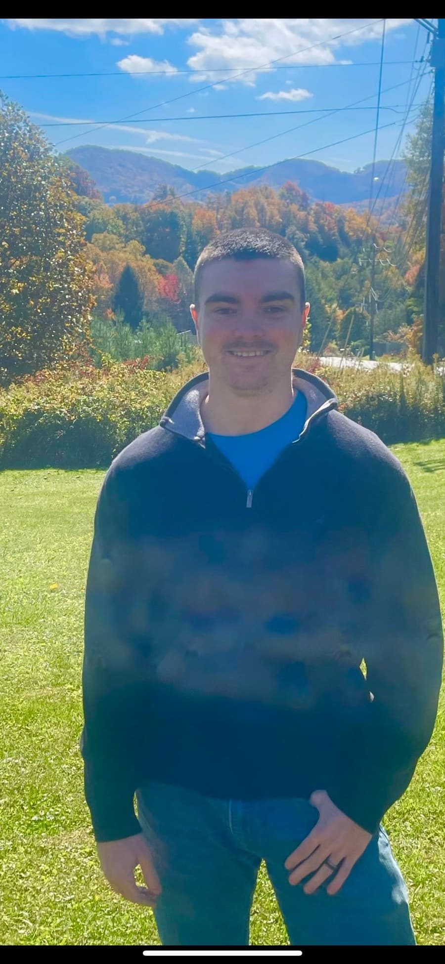 Justin Holland smiling outdoors with autumn mountains in the background